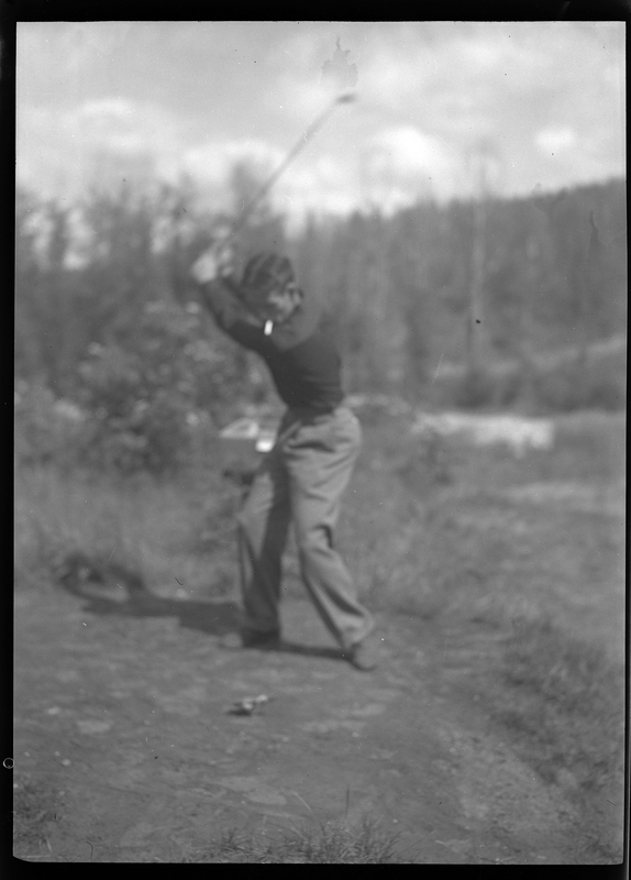 Photo of an unidentified man playing golf at Shoshone Golf Course. The man is mid swing of the golf club and has a cigarette in his mouth.