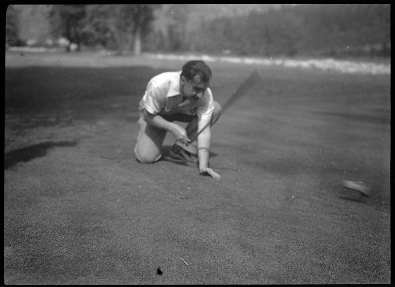 Photo of an unidentified man playing golf at Shoshone Golf Course. The man is knelt on the ground and swinging a golf club.