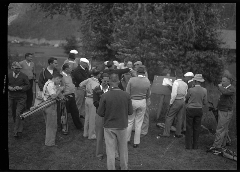 Photo of a large group of men at the Shoshone Golf Course. Some men have golf bags with clubs in them.