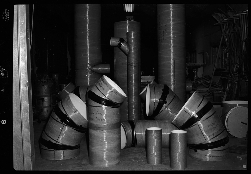 Photo of Spunstrand Incorporated equipment in a room, possibly HVAC system work. There are several tubes with curves in them coming out of the floor, none of which are connected.