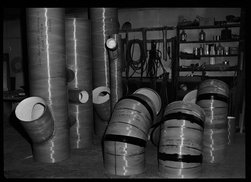 Photo of Spunstrand Incorporated equipment in a room, possibly HVAC system work. There are several tubes with curves in them coming out of the floor, none of which are connected.