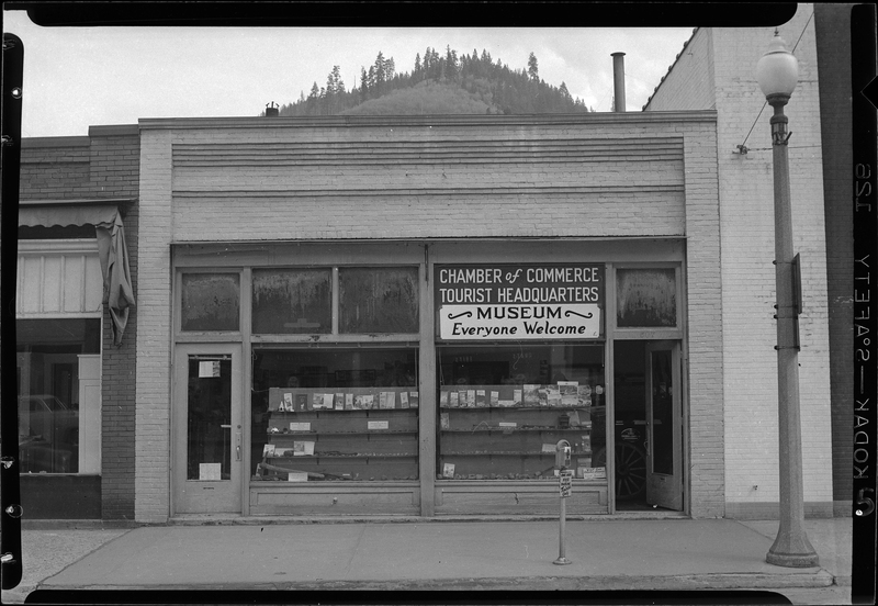 Photo of the exterior storefront of the Wallace Chamber of Commerce building. The front door is open and there is a sign that reads "Chamber of Commerce; Tourist Headquarters; Museum; Everyone Welcome."