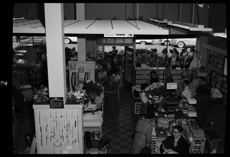 Several unidentified people, mostly women, are shopping inside of Henry Kuhlruss' clothing and shoe store during their grand opening.