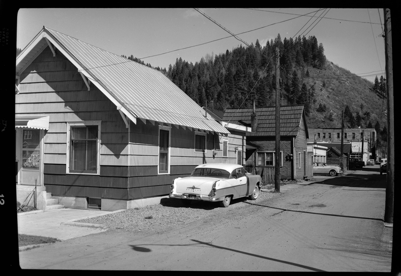 Photo of a car parked on the side of the road next to a house. Labelled as "Magnuson Project, Stardust Motel."