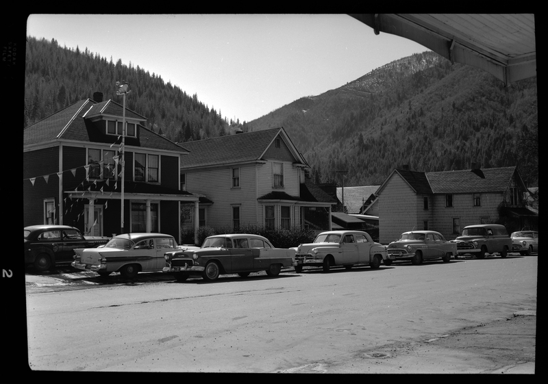 Photo of a line of cars parked on the side of the road in front of some houses. Labelled as, "Magnuson Project, Stardust Motel."