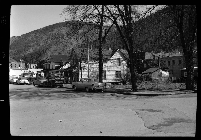 Photo of a handful of cars parked on the side of the road in front of some houses. Labelled as, "Magnuson Project, Stardust Motel."