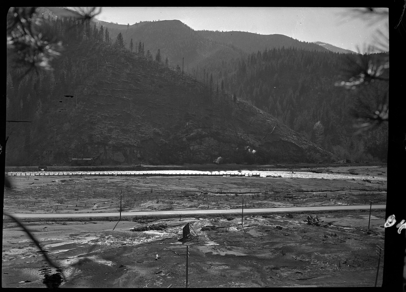 Photo of an unidentified outdoor scene. The area is muddy and empty, and there is a river in the background.