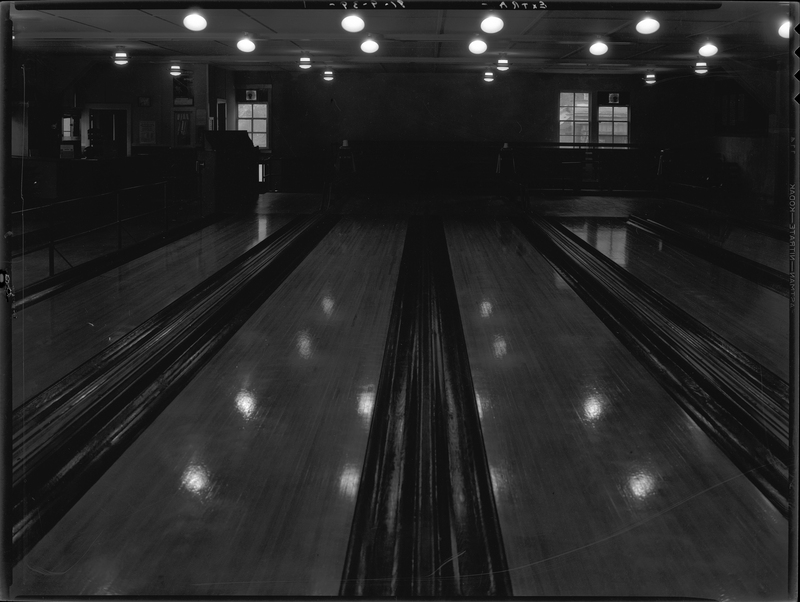Photo of the Wallace Bowling Alley lanes looking towards the standing area. The photo is very dark.