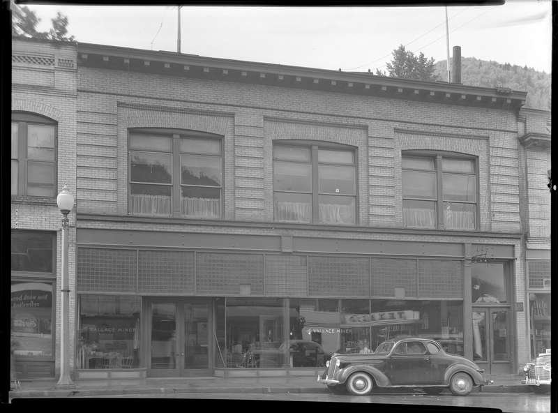 Photo of an unknown building (possibly the Labor Building on Bank Street) including the Wallace Miner and Employment Office F. M. & S. Company. There are two cars parked on the side of the road in front of the building.