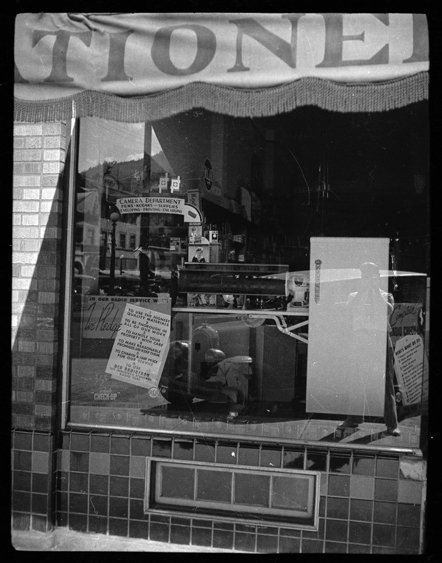 Photo of a window display in an unidentified store. There are cameras on display and a sign that reads, "1. to use the highest quality materials; 2. to be thorough in all of our work; 3. to handle your property with care; 4. to make reasonable promises and keep them; 5. to charge a fair price for our service; 6. to use RCA Radiotron the industry's standard radio tube."