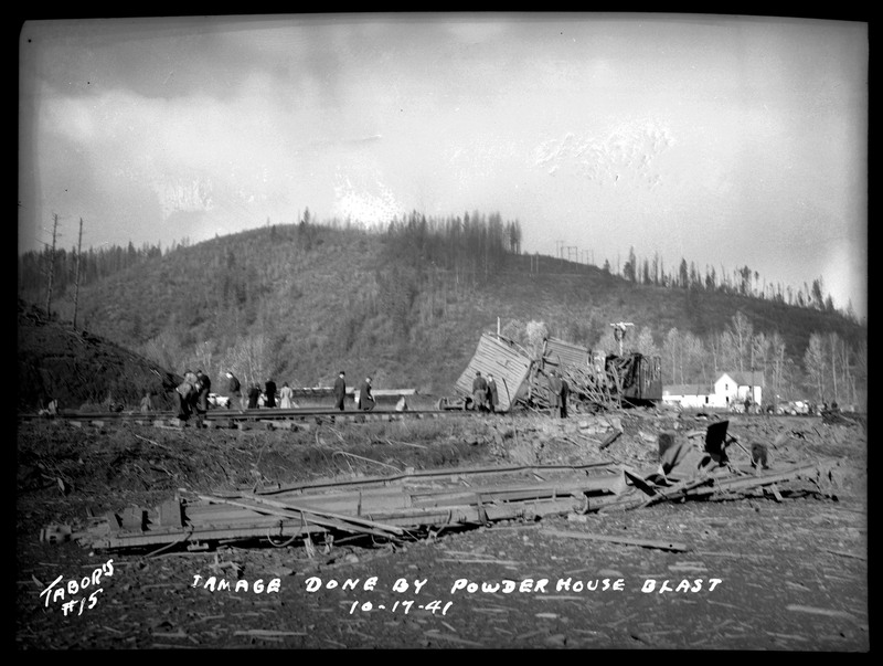 People inspecting railroad cars and tracks damaged by the explosion of the Sunshine Mine powderhouse.