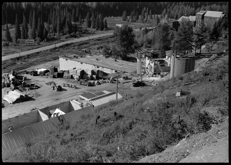 The exterior of Lucky Friday mill facilities and buildings which are under construction, including what appears to be silos for holding mineral materials. Workers are on several of the structures and facilities. 