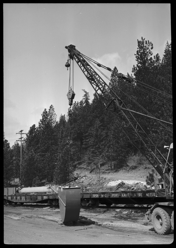 A disassembled mine hoist on a train at the Lucky Friday Mine near Mullan, ID. A crane is loading or unloading parts from the train. 