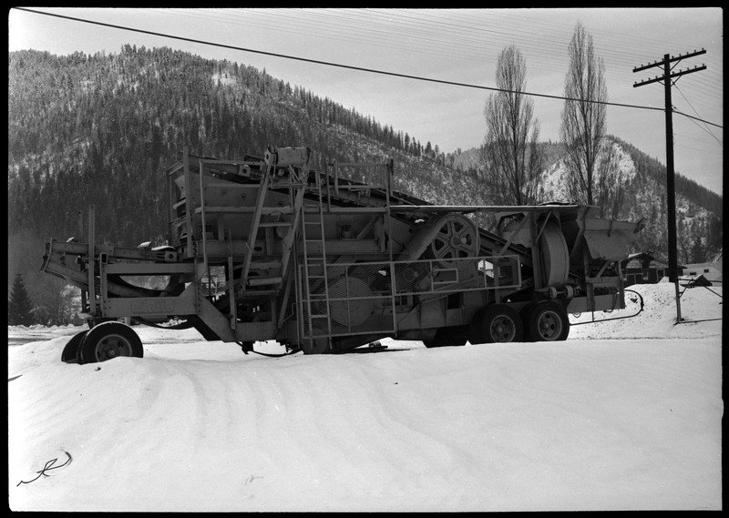 Atruck used by Coeur d'Alene Mining Company. The truck appears to also serve as mining machinery, and it is parked outside in the snow.