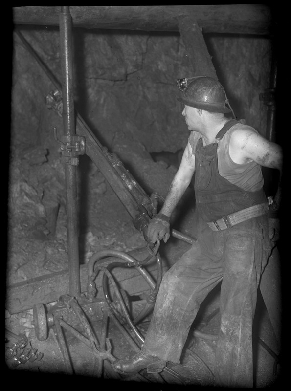 A man operating a mine hoist in an unidentified mine.