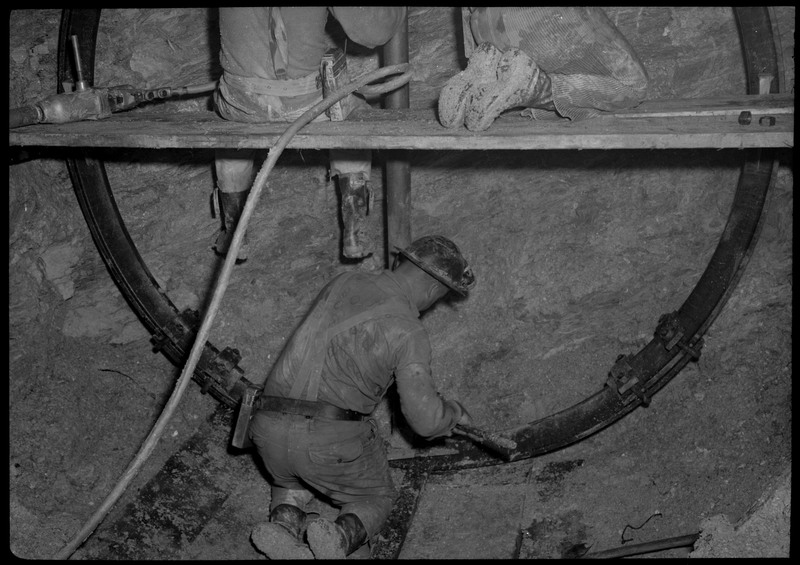 Three men working inside of Silver Mountain mine. They are working at the end of a tunnel.
