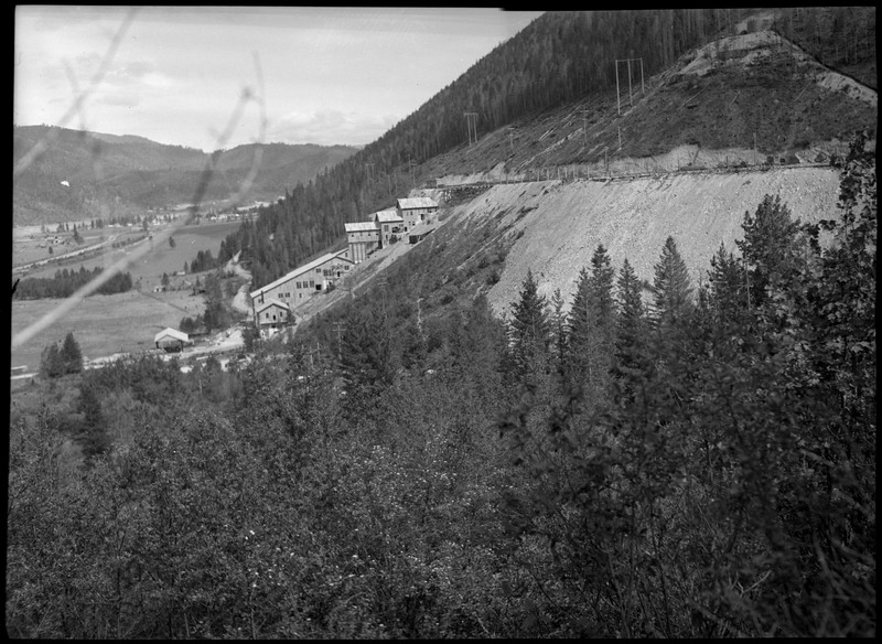 Image of the Silver Summit mine complex from a distance. There are trees between the photographer and the mine.