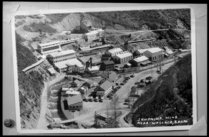 Image of a photograph of Sunshine Mine near Wallace, Idaho. The photo overlooks all of the mining complex, showing numerous buildings and vehicles.
