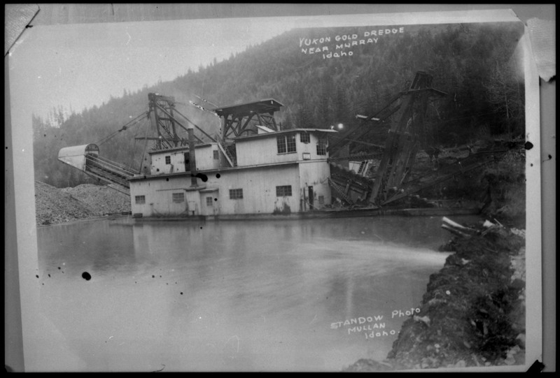Image of a photograph of the Yukon Gold Dredge near Murray, Idaho. The dredge is located in a river or lake.