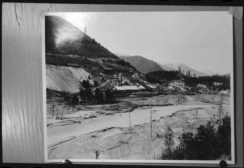 Image of a photograph of Morning Mill. There is a river between the photographer and the milling complex. There appears to be snow on the ground and some of the roofs of buildings.