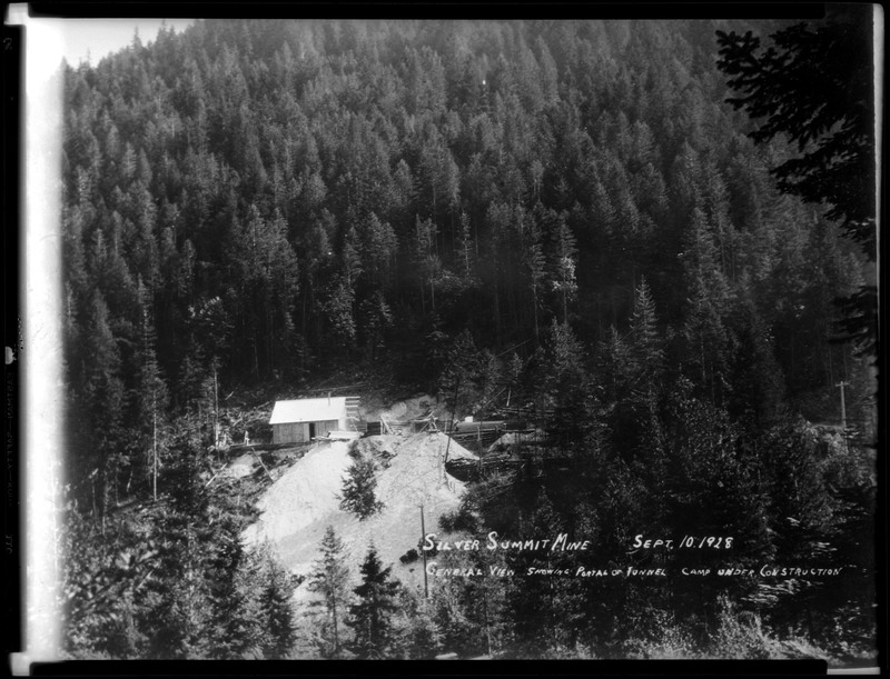 General view of Silver Summit Mine showing portal of tunnel and camp under construction. The mine is in the distance, partially obscured by trees.