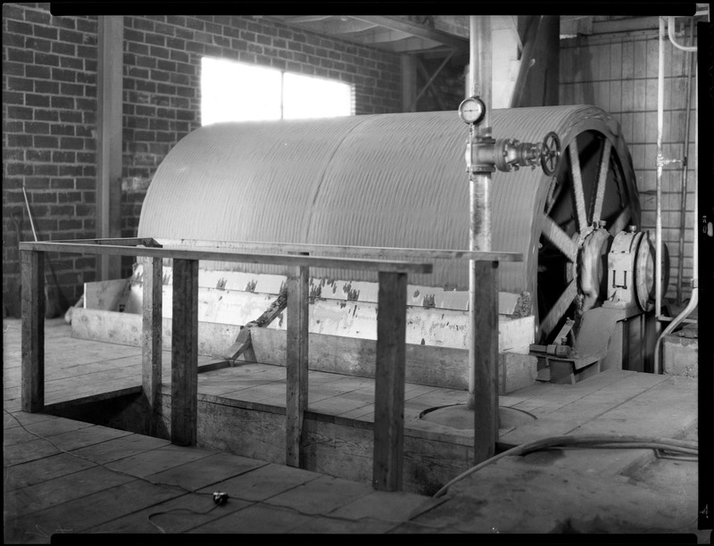 Mining machinery at the Hecla-Star Mill. A window is in the background. A hole in the wooden floor is in front of the machinery.
