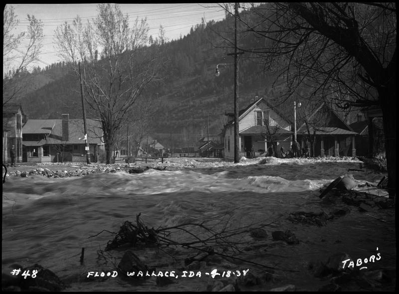 The Wallace, Idaho flood in front of some residential houses. There are people standing outside.