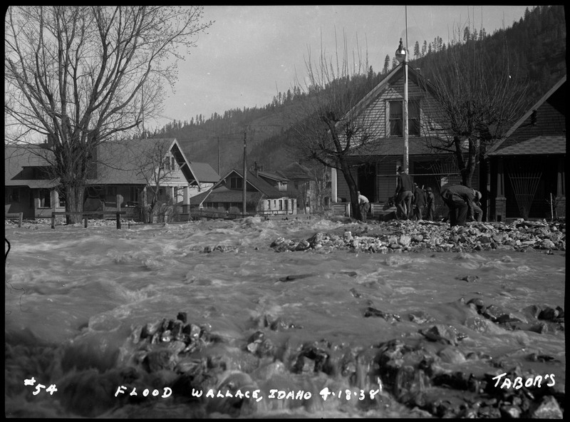 The Wallace, Idaho flood in front of some residential houses. There are people standing outside.