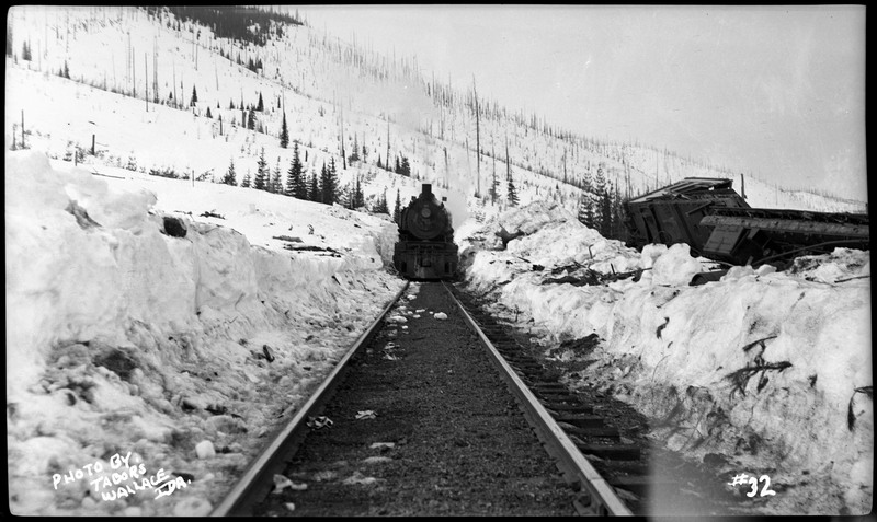 The train tracks in the snow near the flood near Wallace, Idaho. One of the train cars has been pushed off the tracks and into the snow, presumably by the flood.