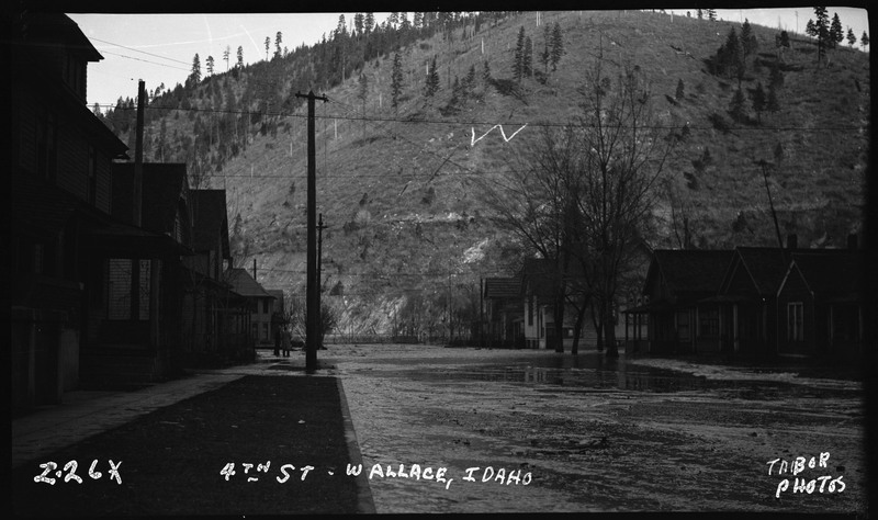 4th Street in Wallace, Idaho during a flood. There is water overflowing in the streets and up to the houses.