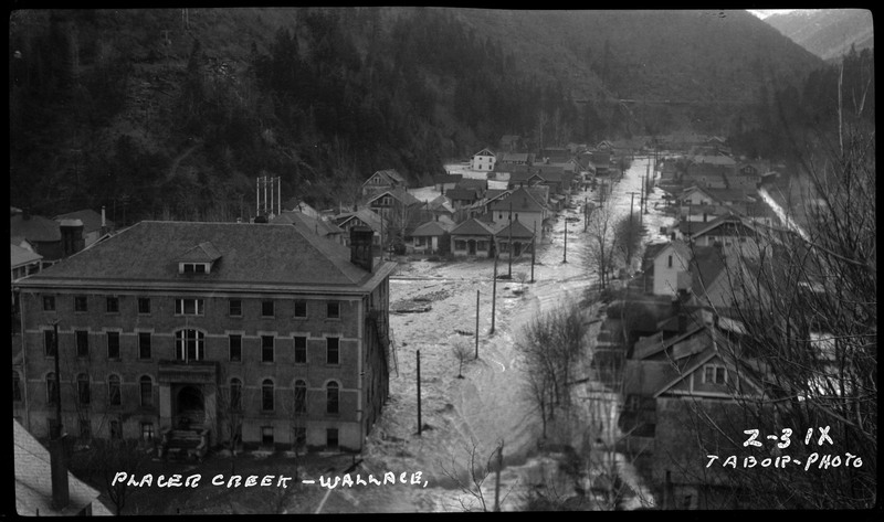Image overlooking Placer Creek in Wallace, Idaho during a flood. The water is in the streets and rushing up to the buildings.