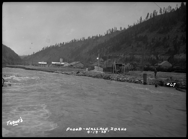 Landscape view of a flood in Wallace, Idaho. A person can be seen near the water on the right.