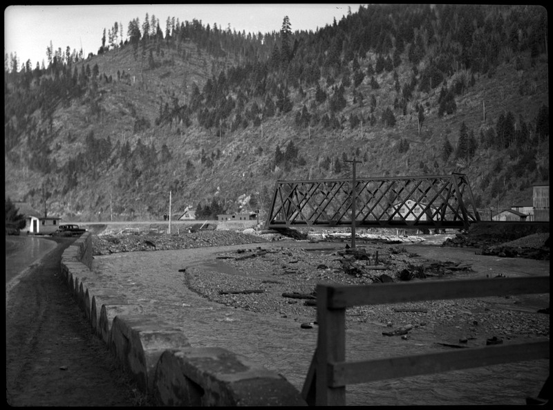 Bridge after a flood in Wallace, Idaho. There is debris piled between the bridge and the road.
