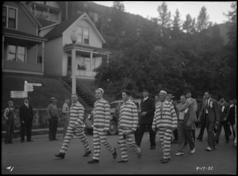 Men walking in the Benevolent and Protective Order of the Elks Roundup parade. Some men are wearing striped suits.