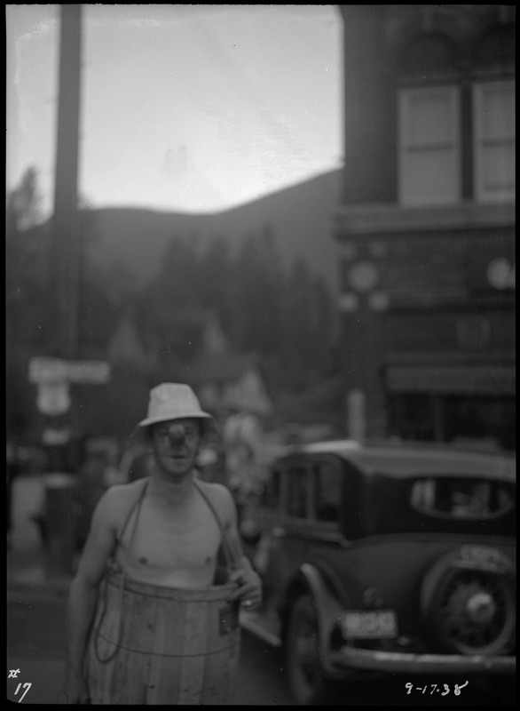 A man wearing a barrel and a clown nose during the Benevolent and Protective Order of Elks Roundup parade. The background of a vehicle and street scene is blurred.