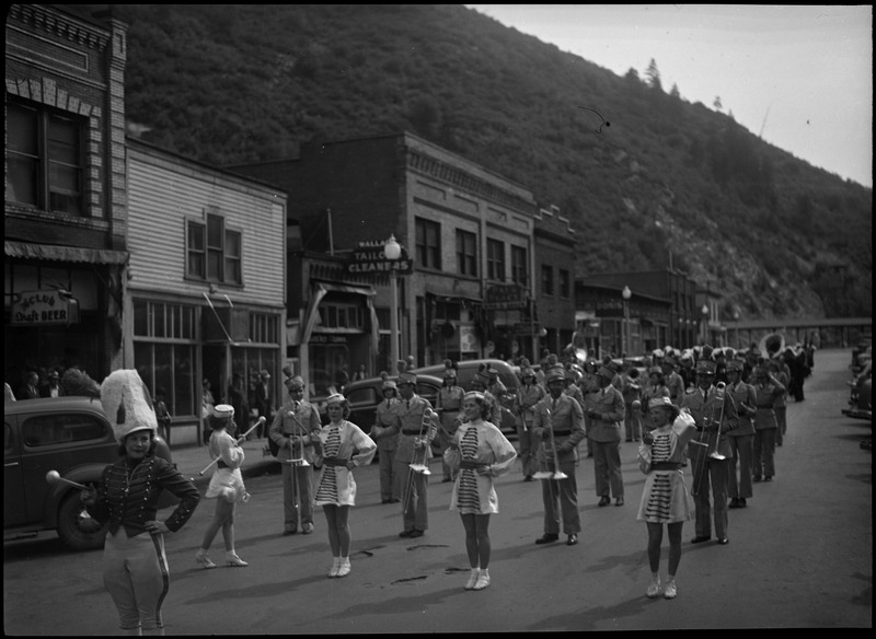 Band members, a few women and mostly men, in the Benevolent and Protective Order of Elks parade. Spectators are watching in the background on the sidewalks.