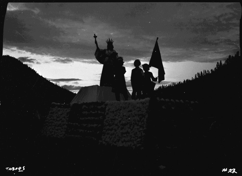 A darkened image of the C.U.C. float in the Elks Roundup parade. A woman posing as the Statue of Liberty stands with three other people on the float.