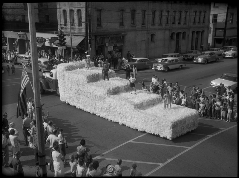 Four children standing on a float during the Benevolent and Protective Order of Elks roundup parade. Spectators watch in the street and from the sidewalk.