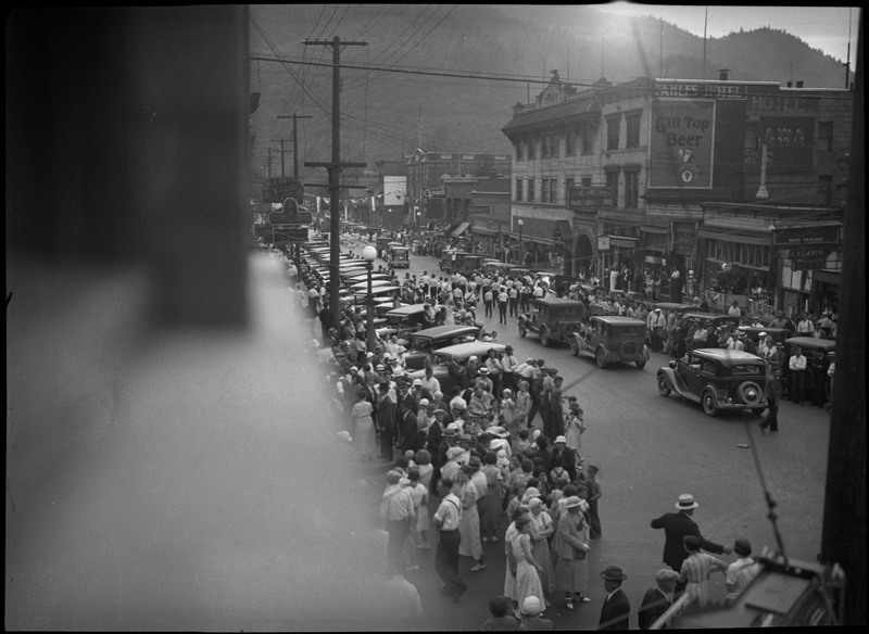 View of the procession in the street during Benevolent and Protective Order of Elks parade. The street is crowded with spectators.