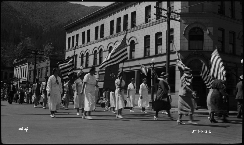 Women walking in Memorial Day parade holding American flags.