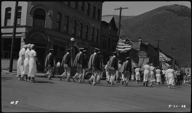 Men and women, some holding American flags, walking in Memorial Day parade. 
