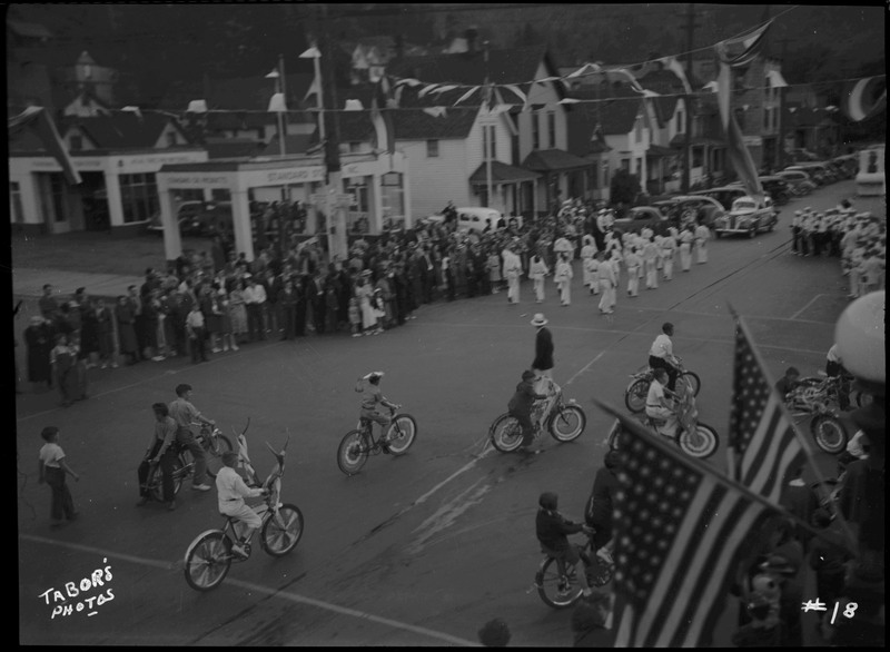 Children on bicycles and in marching band during B.P.O.E. parade. Crowds of spectators watch from the sides of the street.