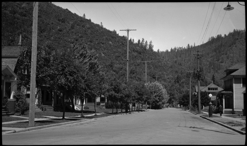 View of empty street in Wallace, Idaho. Trees and buildings are in view.