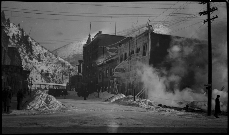 View of the Ryan Hotel and Tabor Building fire. The street and buildings are covered in snow. A person can be seen standing on the right.