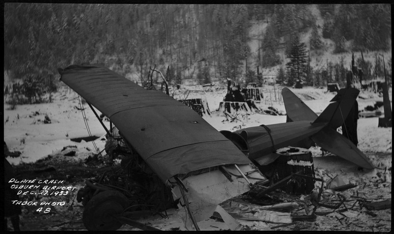 Debris from an airliner crash. Snow covered trees and tree stumps in the background. Caption on the bottom left of the photograph reads "Plane crash Osburn Airport Dec. 27, 1933 Tabor Photo 48"