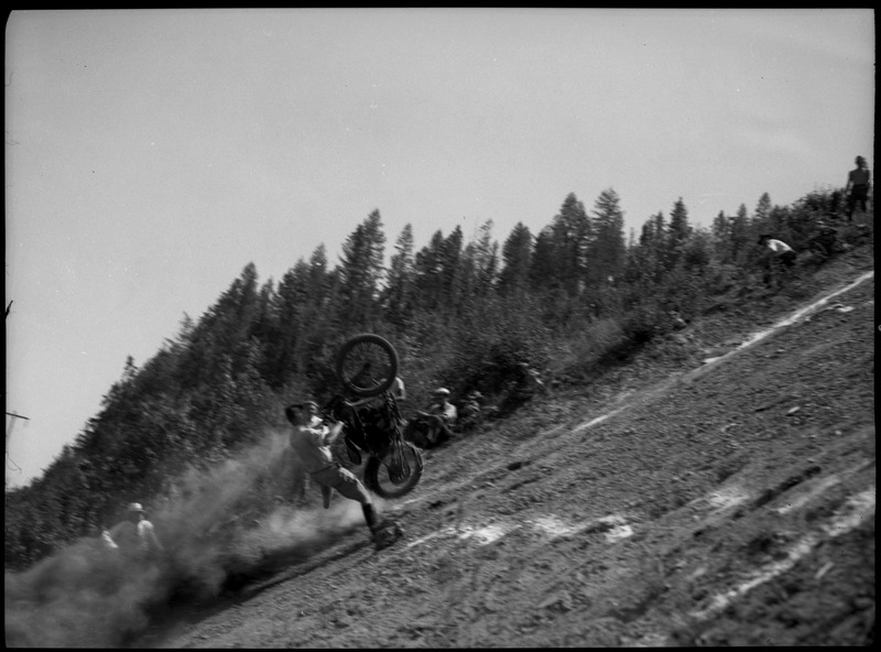 A man flying off of his motorcycle, which is vertical during a steep motorcycle hill climb.