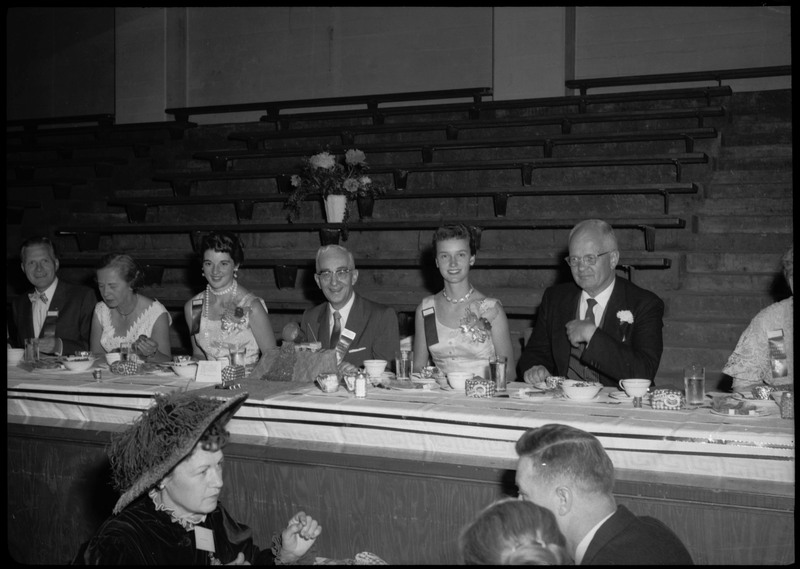 People dressed in formal wear seated at a table in front of bleachers during the Silver Jubilee banquet.