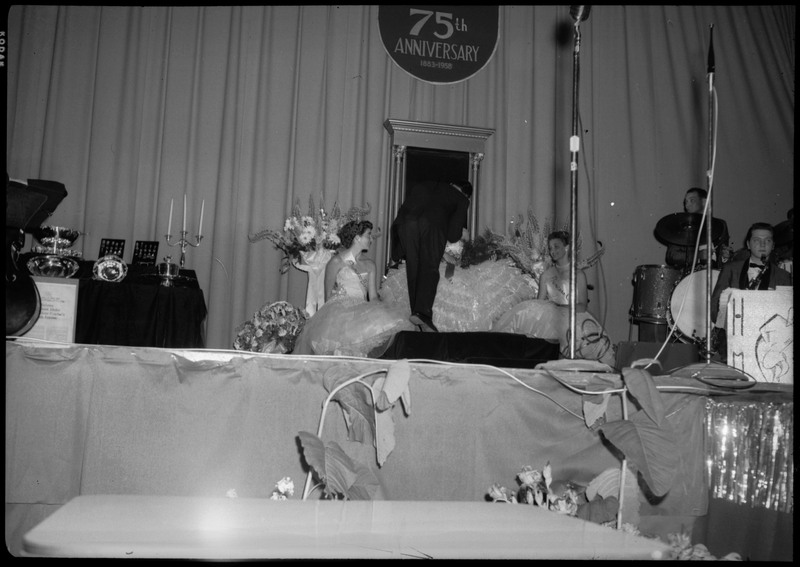 Part of a band and women wearing fancy dresses on the stage during the Silver Jubilee banquet.