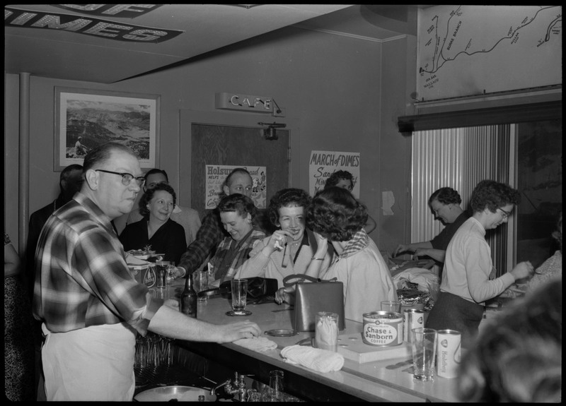 People sitting at a bar area during the Albie's March of Dimes event. A man wearing an apron is standing behind the bar.