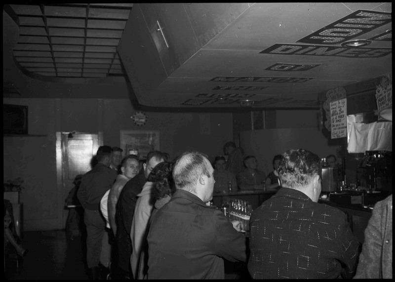 Image of the bar area and people standing behind the bar area during the Albie's March of Dimes event. There is decorative text on the ceiling.